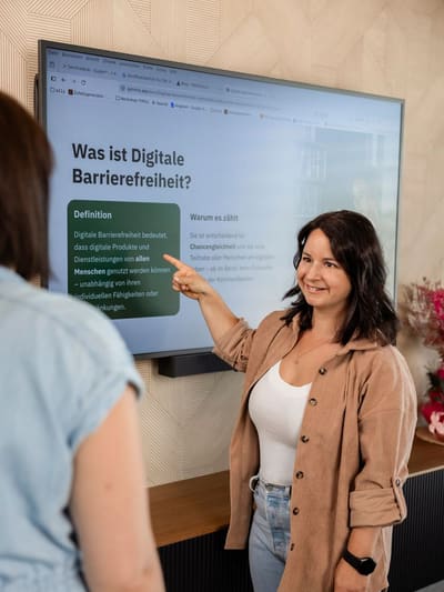Elisabeth Zeilinger zeigt in einem Workshop auf eine Folie mit der Überschrift „Was ist Digitale Barrierefreiheit?“